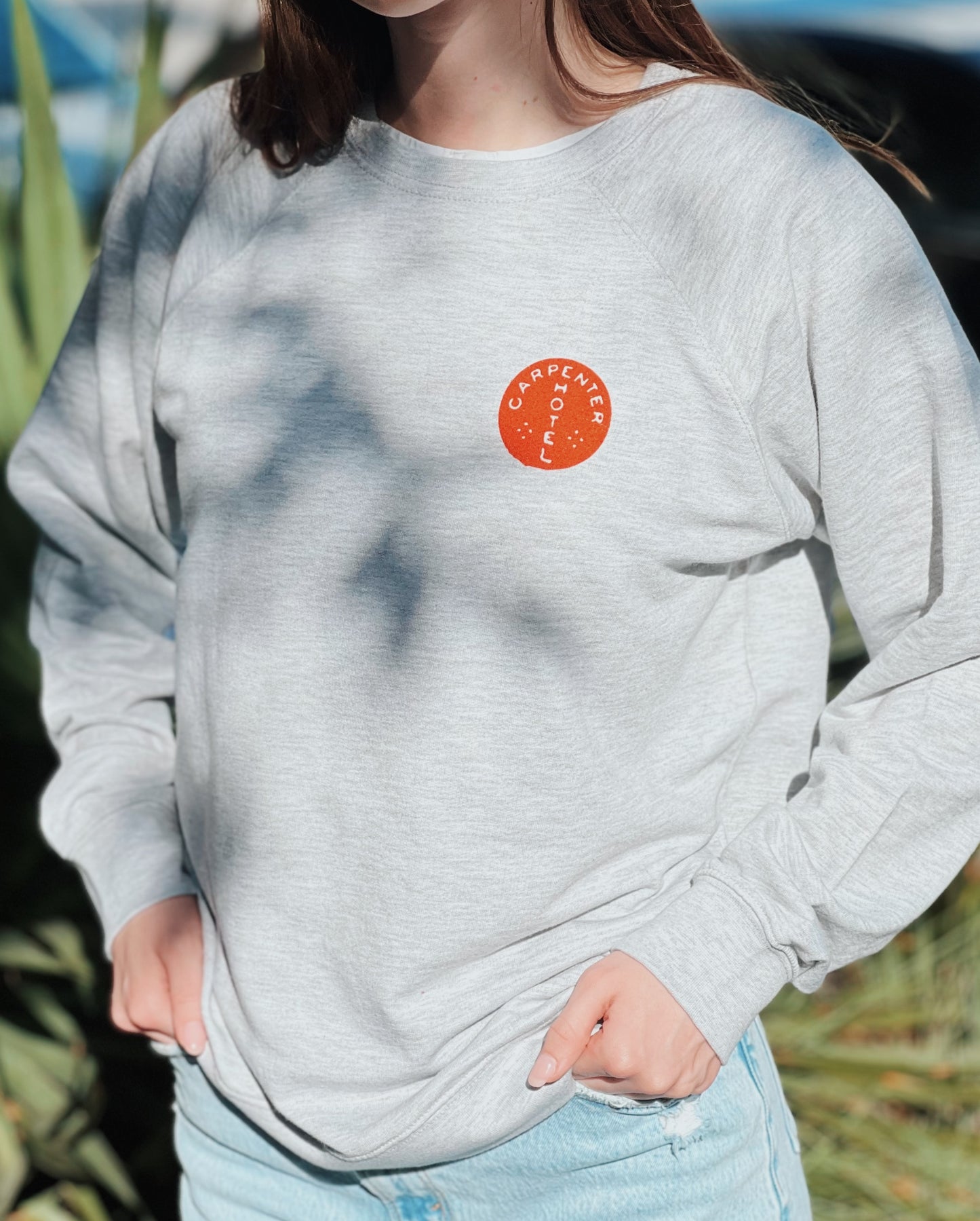 Person wearing a gray sweatshirt with an orange logo outdoors