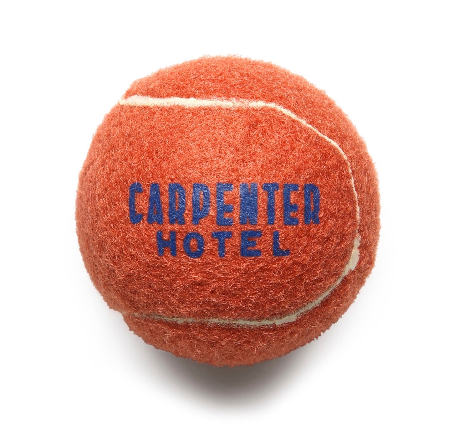 An orange tennis style dog ball with 'CARPENTER HOTEL' printed in blue text on it.