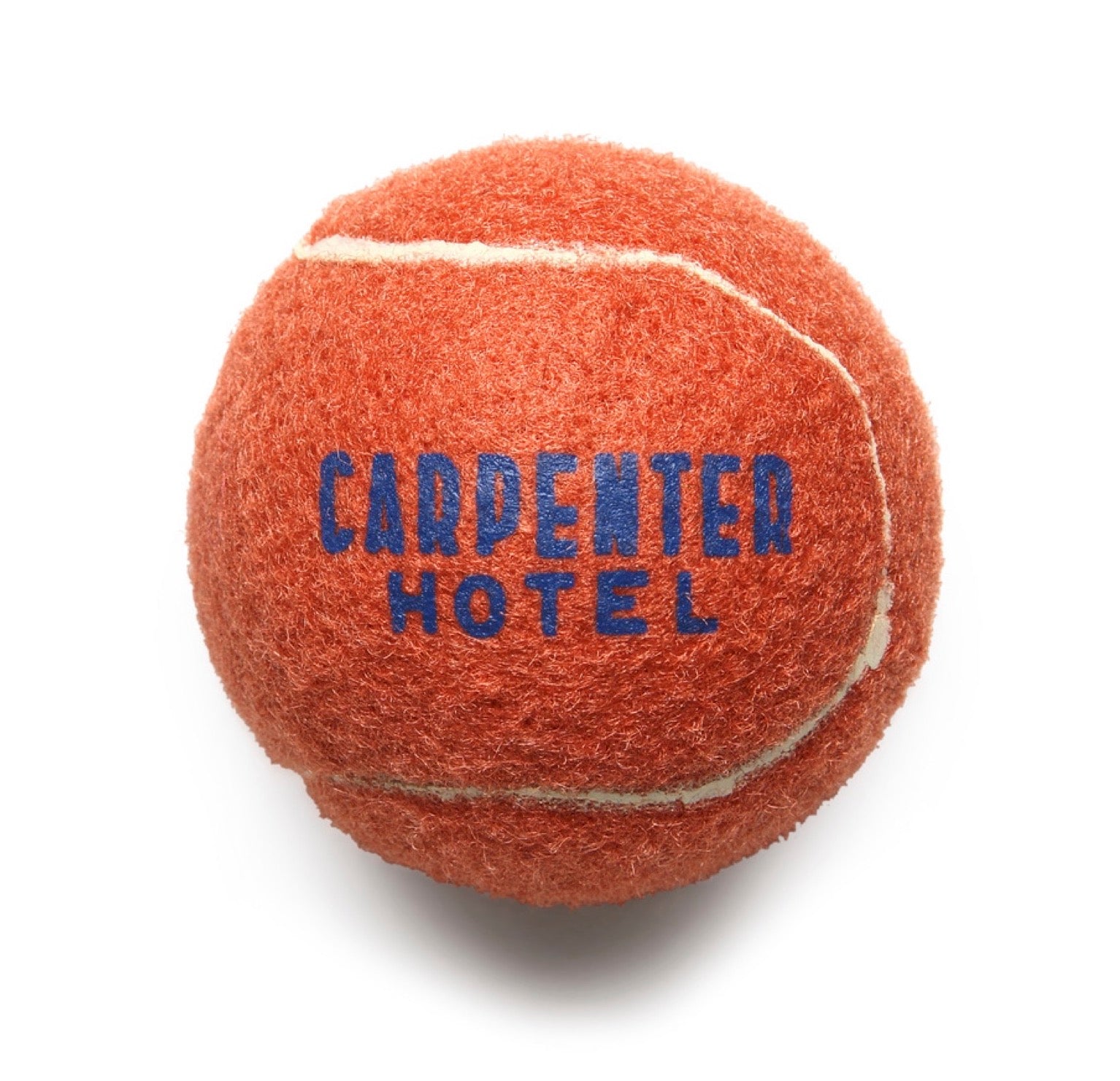 An orange tennis style dog ball with 'CARPENTER HOTEL' printed in blue text on it.